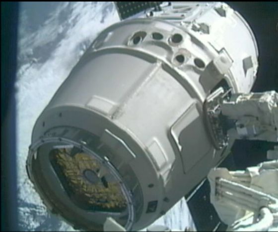La nave Dragón sujeta por el brazo articulado de la Estación Espacial Internacional