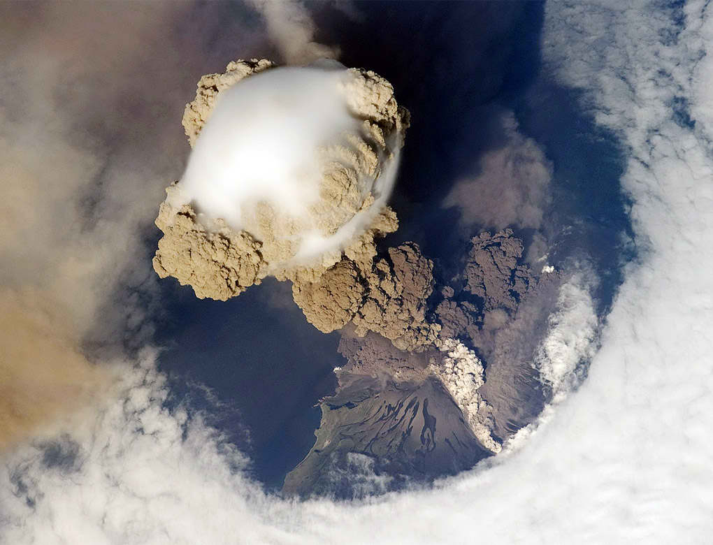 Fotografía  del volcán Sarychev en el momento en que ocurre una explosión del volcán, abriendo un agujero en las nubes que flotan sobre él y lanzando hacia el cielo una densa acumulación de cenizas, fue tomada el pasado 12 de junio, en uno de los primeros momentos de la erupción.